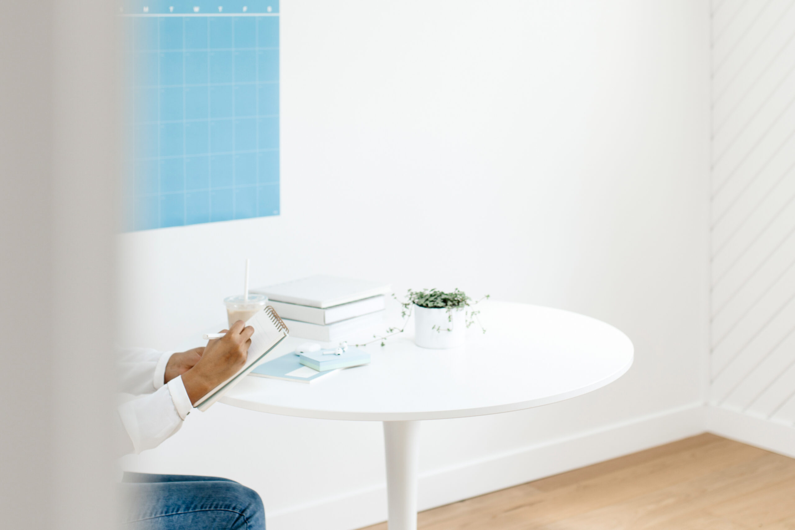 Image of a white table, small blue poster in the back, and a hand leaning over the table.
