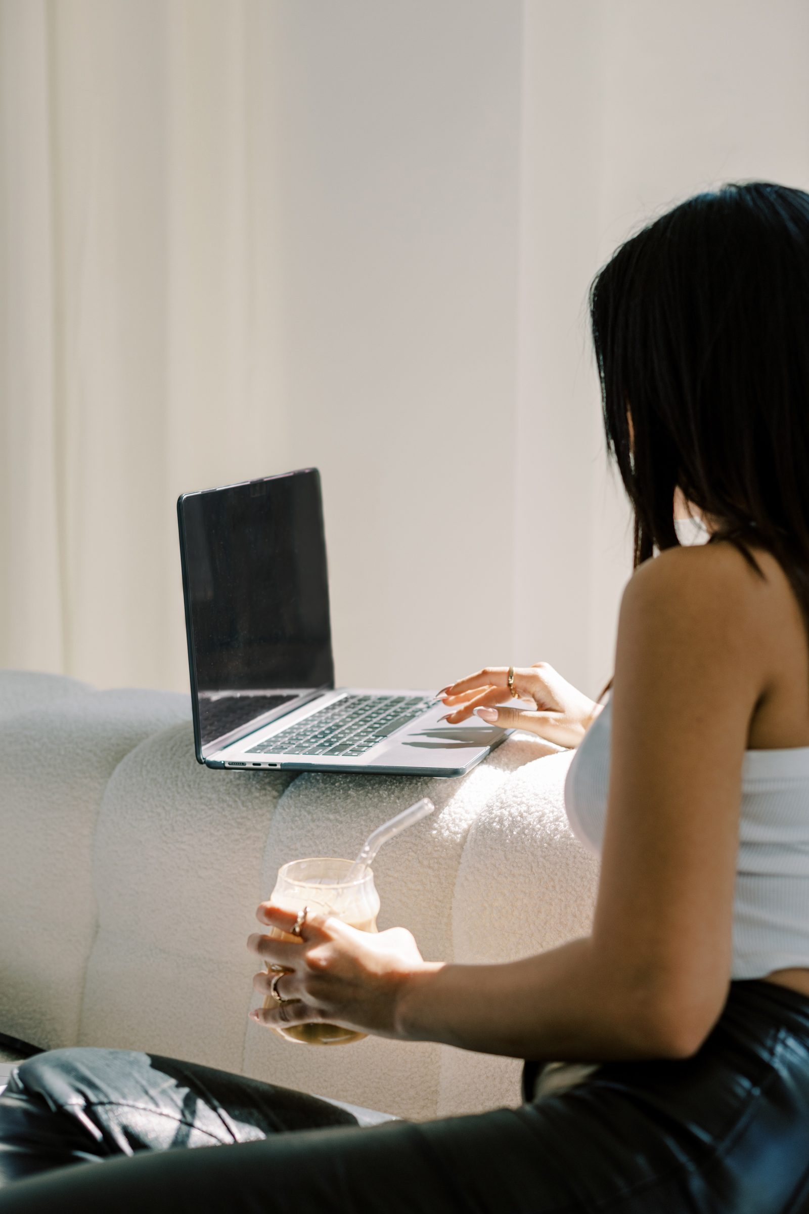 Woman holding coffee while answering emails on laptop