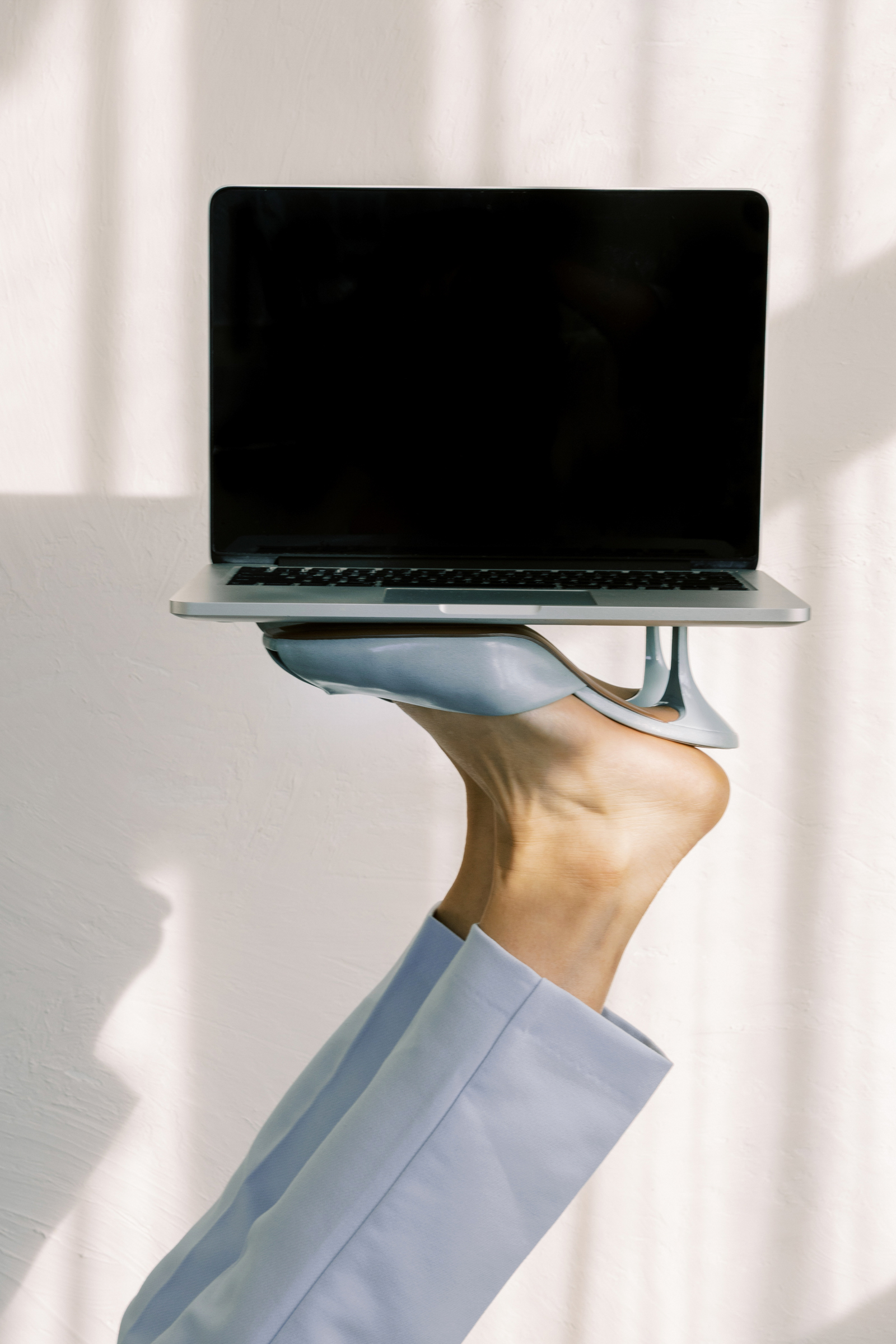 Image of woman holding her laptop up by her sky blue heels